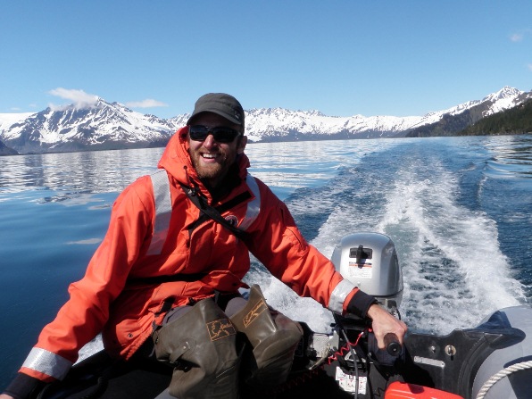 Park researcher drives a small boat through the blue waters of Kenai Fjords National Park. Park researcher drives a small boat through the blue waters of Kenai Fjords National Park.