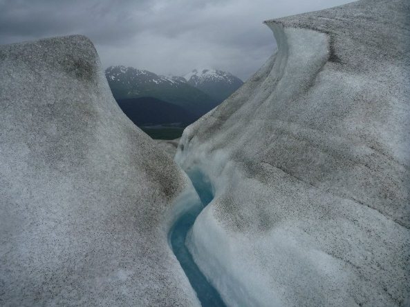 View through a glacier crevass to mountains behind.