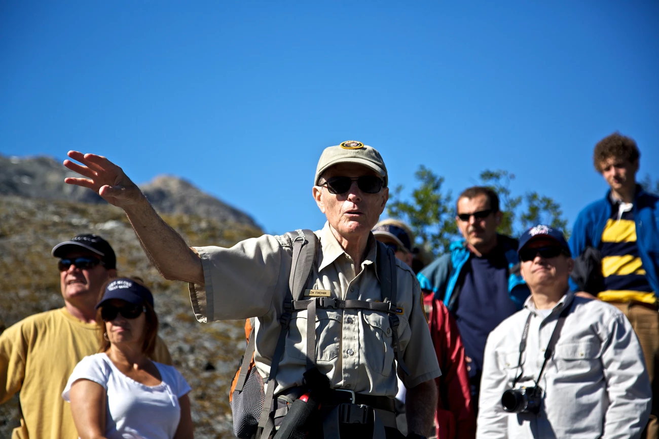 A park volunteer points to show something to visitors