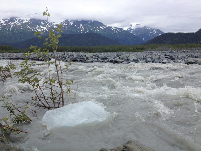 A rushing creek with mountains in the background