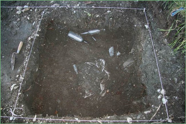 Bottles lie uncovered at the base of an excavation.