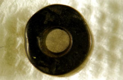 A small, round, black bead with a hole in the middle.