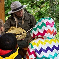 A park ranger holding a bear skull talking to a group of students