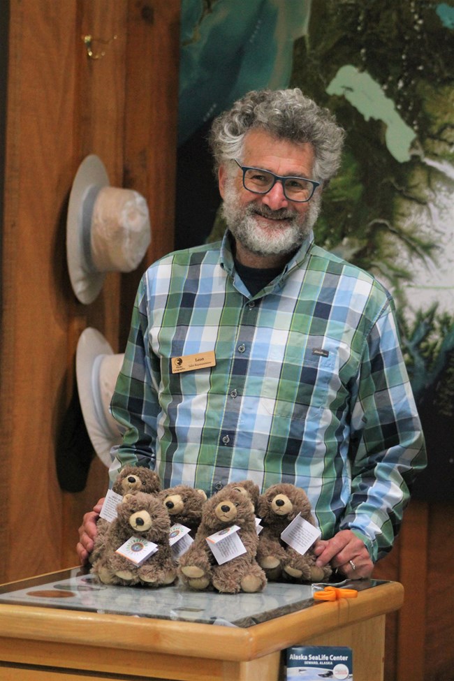 A person stands behind a pile of stuffed toy bears.