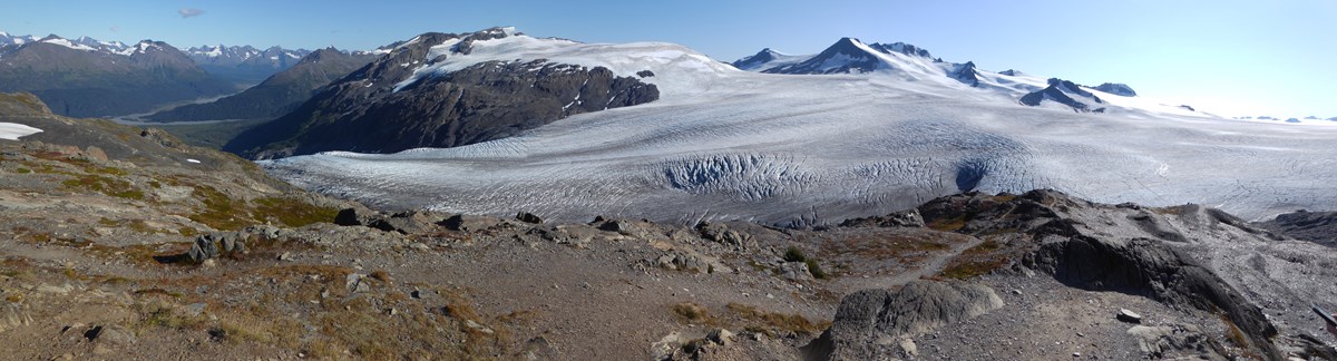 A large field of ice is in the background. In the foreground a path leads to the edge of the icefield