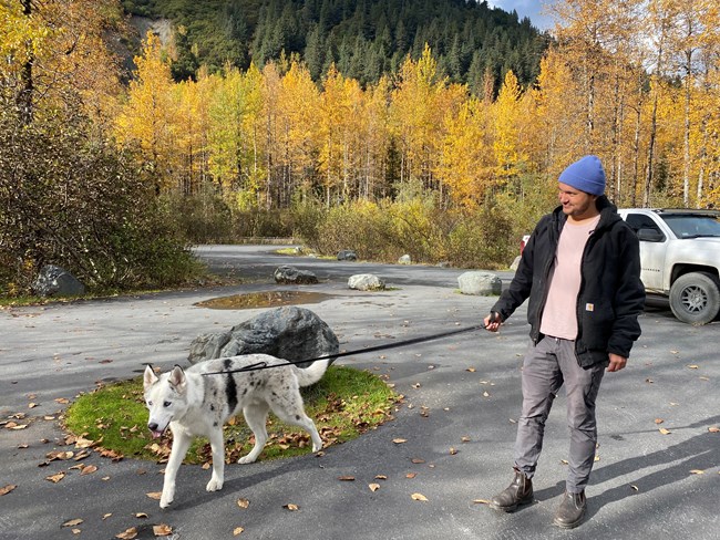 A visitor walking their leashed dog in parking lot