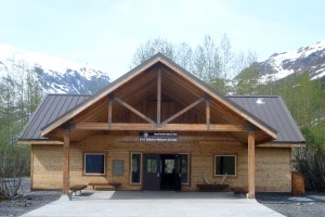 A wooden building with a large awning from the front, providing cover in front of the main double entrance doors.