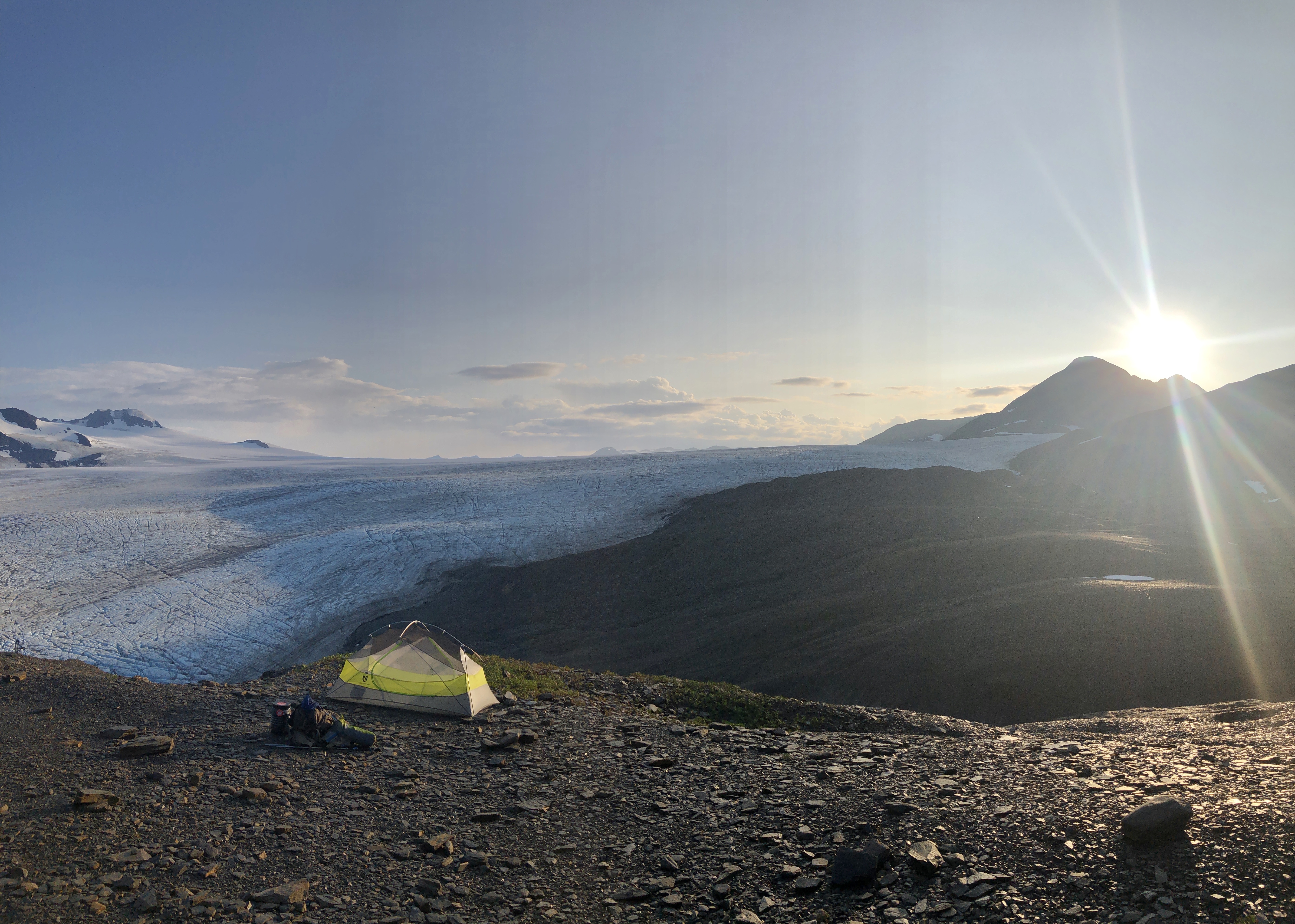 A tent with icefield sunset behind