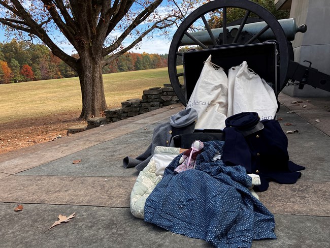 Traveling trunk items displayed with cannon and trees in background.
