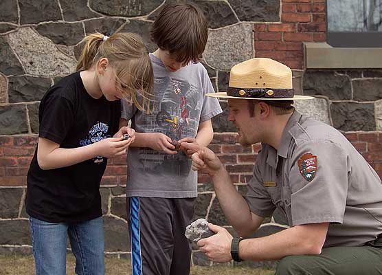 Young visitors and a park ranger take a look at some rock specimens.