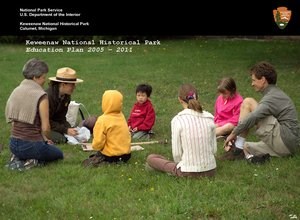 A ranger interacts with young children and their caregivers sitting outside on grass. A ranger interacts with young children and their caregivers sitting outside on grass.
