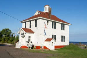 A white exterior two-story buildings with a brown room surrounded by green grass.