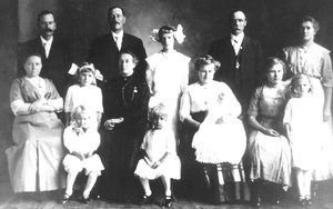 A group of people pose for a photograph, some standing and some sitting.