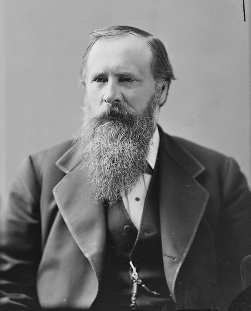 Studio portrait of a seated man from the waist up.