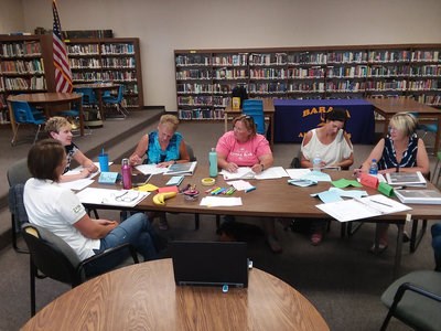 A group of people sit at a table filling out worksheets.