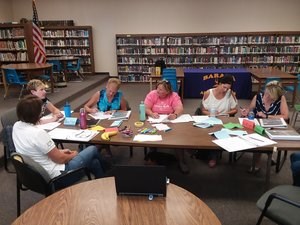 A group of people seated at a table write thoughts down on paper.