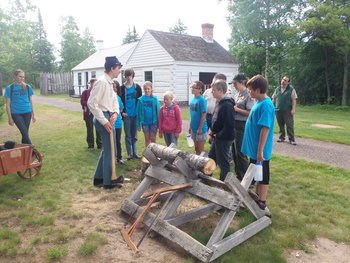 A group of students talk to a young person dressed in historical re-enactment dress.