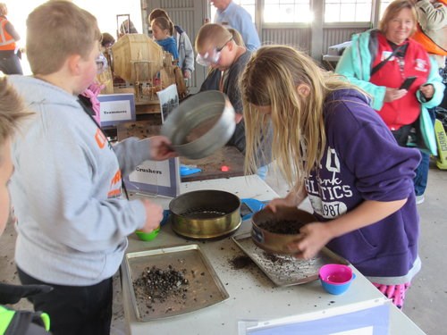 Students use their hands to complete different steps of the copper milling process.