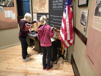 Two kids lift up the top of a desk.