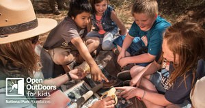 A ranger shows different bones to a small group of children.