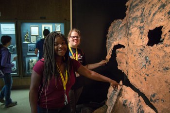 A student points at a large piece of copper inside a museum.