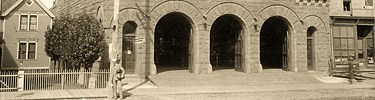 The arched vehicle doors to the Red Jacket Fire Station stand open in this 1904 photograph.