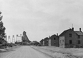 Historic photo: A row of vacant company houses in Lower Pewabic Location leads to the closed #2 Shaft-rockhouse at Quincy Mine. 1941 John Vachon photograph. Courtesy of the Library of Congress