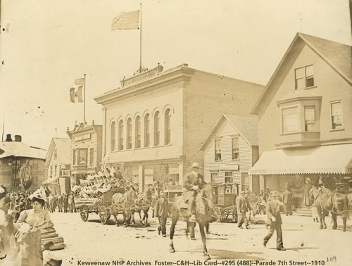 A variety of people walk down a street together in a parade.