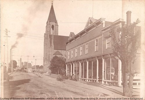 A long building and a church stand next to one another along a street.