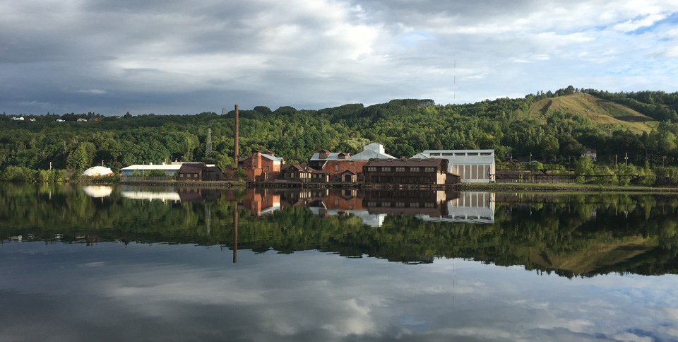 The Quincy Smelter from across the Portage Canal with cloudy skies and glassy water