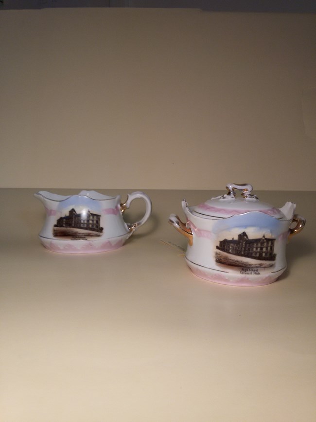 The souvenir creamer and sugar bowl set pictured here once belonged to Mary Stalker Kennedy of Calumet and was donated to Keweenaw NHP by her daughter.  The pieces depict the Washington School, built by the Calumet and Hecla Mining Company in 1875.