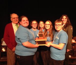 Youth Smackdown winners hold a large trophy and pose for a photo with park staff and volunteers.