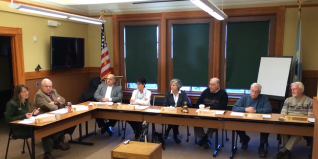 Advisory Commission members sit around a table and discuss topics at a quarterly meeting.