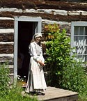 A costumed interpreter at Old Victoria awaits visitors before giving a guided tour of the cabins.