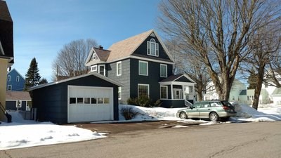 A blue-sided two-story home with a detached garage.