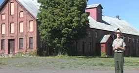 Photo: Ranger Kristen on Mine Street with Calumet & Hecla Warehouse in the background.