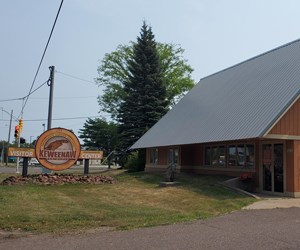 brown painted wood building with a steeply pitched roof, sign to the left reads: Keweenaw Peninsula Visitor Center
