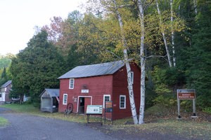 The red exterior of the Bammert Blacksmith Shop and a sign with the site's name.