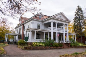The white and pink exterior features of the massive Laurium Manor Inn mix with a backdrop of orange and yellow foliage color.