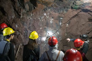 Quincy Underground Tour A group of visitors with hardhats explores the underground of the Quincy.