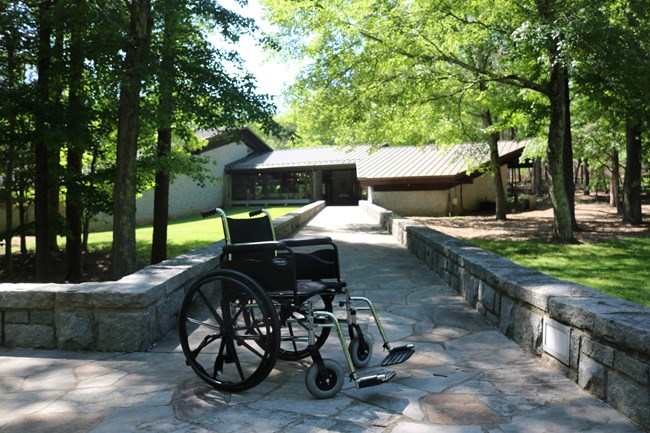 A wheelchair is along a paved ramp to the visitor center.