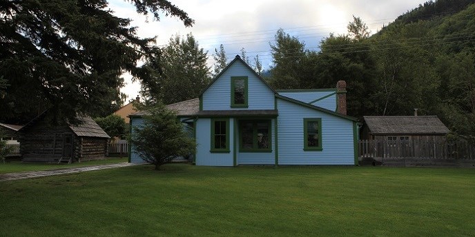 Una casa azul y una cabana con un jardin verde Una casa azul y una cabana con un jardin verde