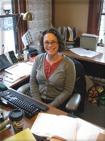 A woman smiles in an office setting. A woman smiles in an office setting.