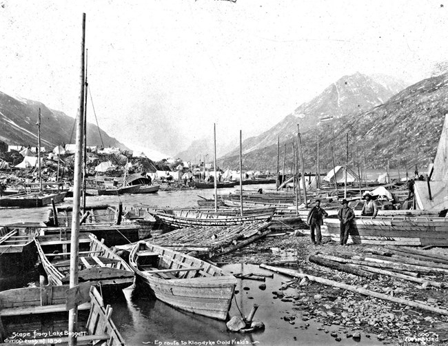 Partially built boats along a lake shore.