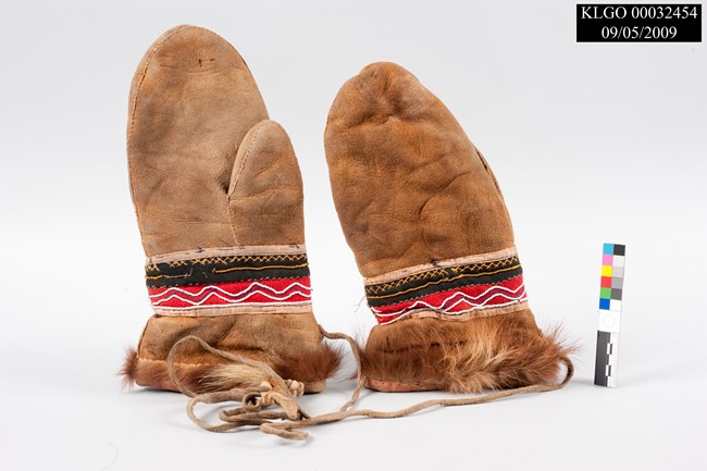 color photo of two brown mittens with red, black, white, and yellow beading around the wrists and edged at the bottom with fur