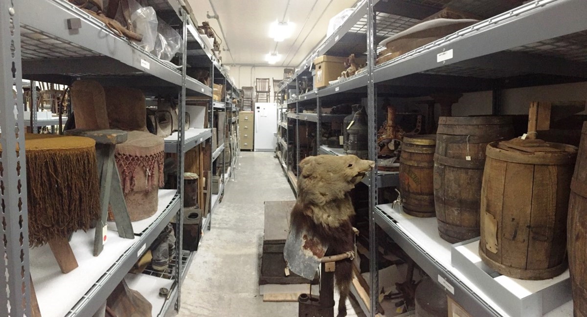 Color photo of a row of gray shelves holding various museum collection artifacts