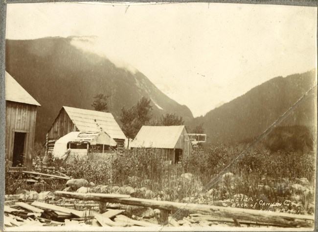 Black and white photo of abandoned buildings in a narrow canyon