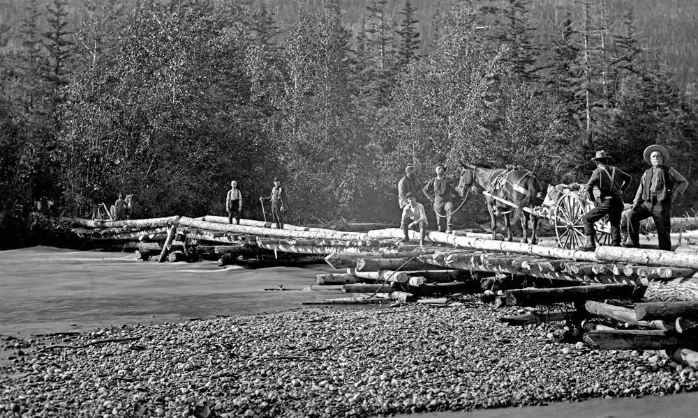 Men and a horse drawn cart on a rustic log bridge