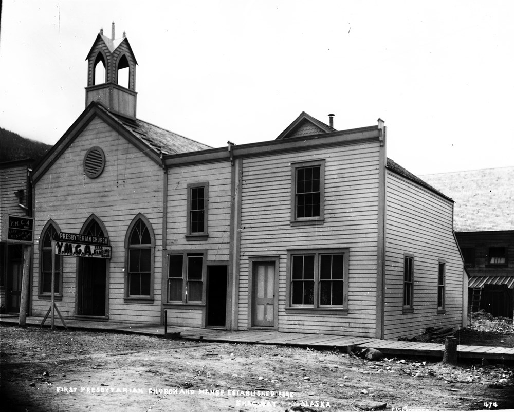 Black and white image of church with sign reading "Presbyterian Church, Y.M.C.A. free reading room"