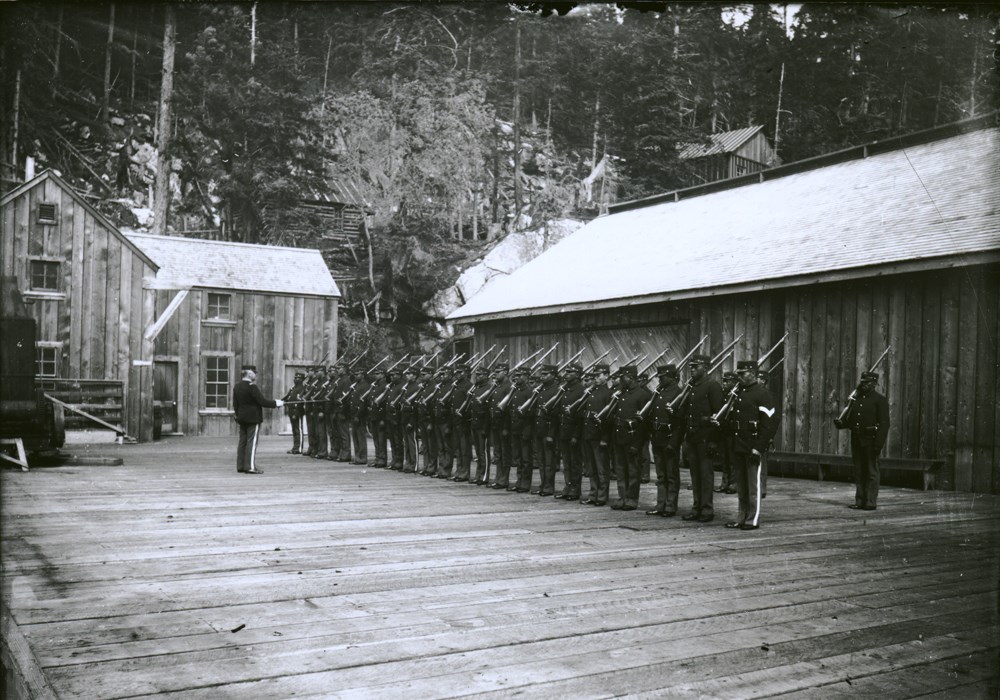 Uniformed soldiers stand in lines on a wooden platform